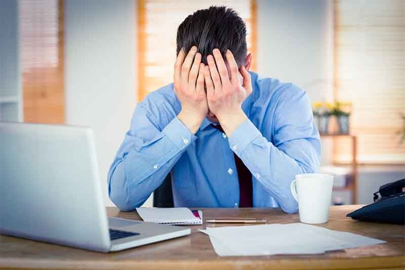 Stressed businessman with head in hands at office, website not performing, traditional website methods